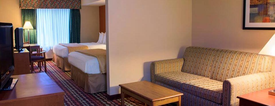 View of the Family Suite with 2 Queen Beds and Mini-fridge and semi-private Living Area with Sleeper Sofa at the Best Western Ambassador Inn Wisconsin Dells