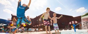 View of kids jumping in the large outdoor pool with water slide in the background of the Outdoor Water Park Thunder Bay at Great Wolf Lodge in Wisconsin Dells